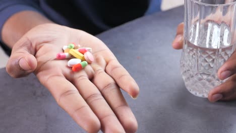 person holding pills and a glass of water