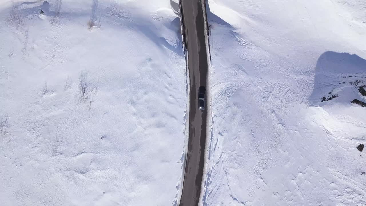 눈이 많이 내리는 산악 구불구불한 도로에서 운전하는 자동차의 하향식 드론 보기