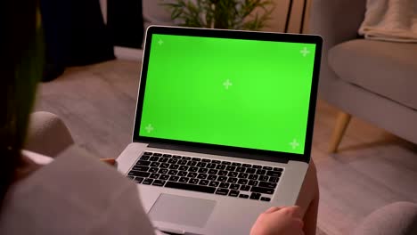 fotografía de cerca de una joven caucásica sosteniendo la computadora portátil con pantalla de tecla de croma verde en homa en el interior