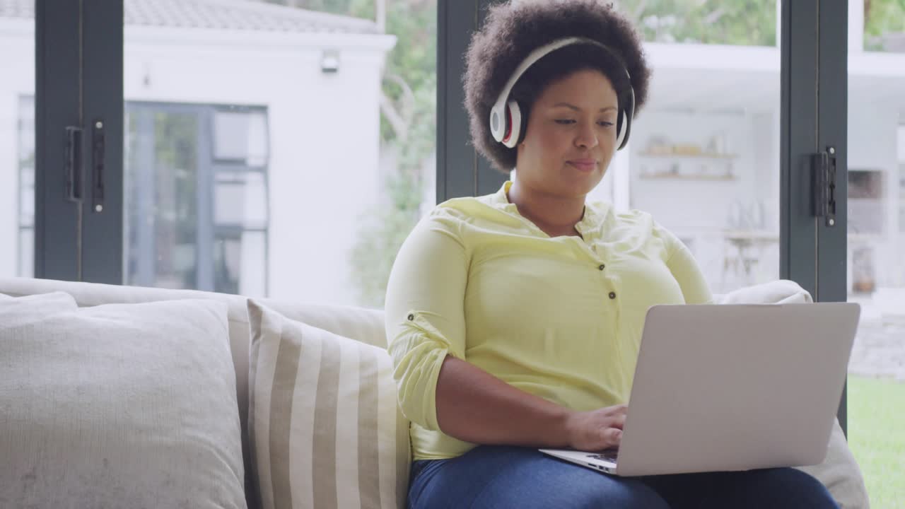 Woman typing on laptop by glass doors, social media alerts around laptop, reaching, checking phone