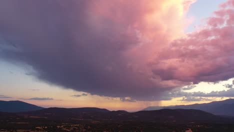 vuelo lateral en el valle de tietar al atardecer visualizando un cielo con una gran nube donde cae la luz y aparecen colores muy llamativos, una parte con cortinas de lluvia vemos colinas y montañas
