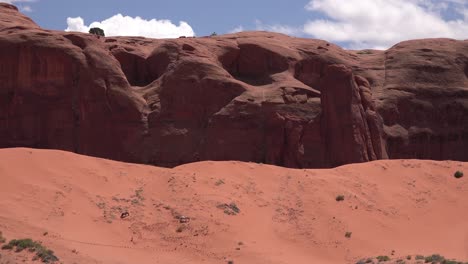 Horses-graze-in-the-distance-against-desert-cliffs