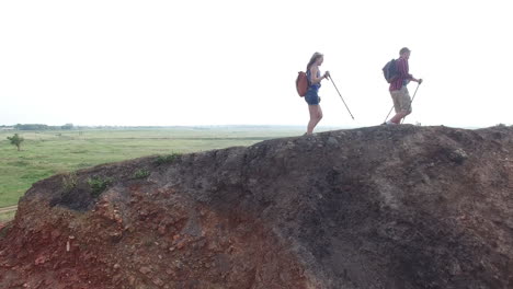 pareja haciendo senderismo por la montaña con vistas a un vasto prado