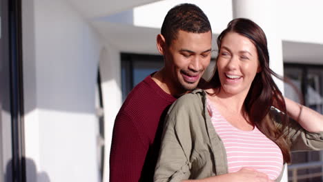 embracing and smiling, couple outdoors with man touching woman's pregnant belly