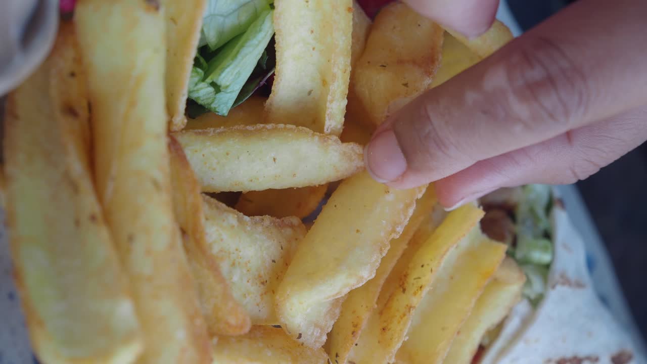 Close-up of a Hand Picking Up Golden French Fries