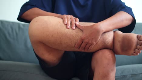 close up of young man massaging swollen leg with hands to relieve discomfort