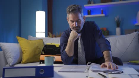 hombre de negocios reflexivo mirando las carpetas de archivos en su casa moderna pensando en futuras ideas de planes corporativos exitosos.