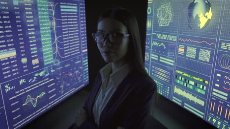 the businesswoman standing between blue screens in the dark lab