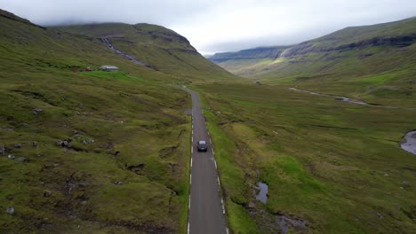 spectacular aerial following car driving on rural faroese road, epic landscape
