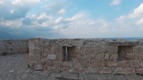 view through arrowslit of kyrenia castle revealing old harbour with moored boats - wide push in through shot