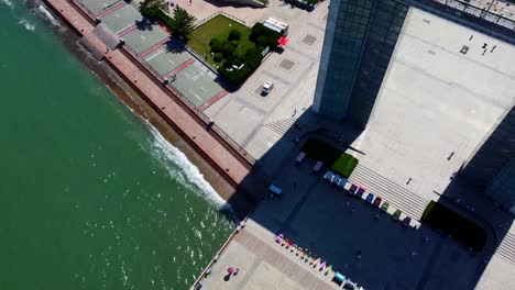 Aerial-tilt-up-plus-helix-panoramic-view-of-Weihai-Xingfu-park-wharf-with-tourists-standing-on-ancient-scribed-mini-dome-and-beautiful-cityscape