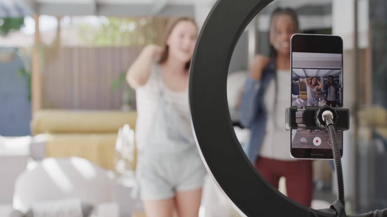 Happy diverse teenage female friends dancing and making video blog with smartphone in slow motion