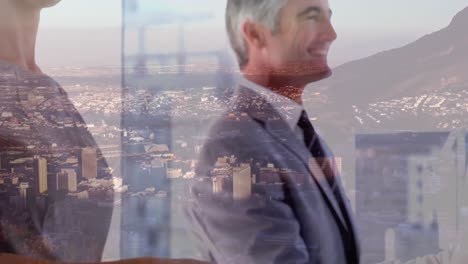 Mid-section-of-businessman-and-businesswoman-shaking-hands-at-office-over-aerial-view-of-cityscape