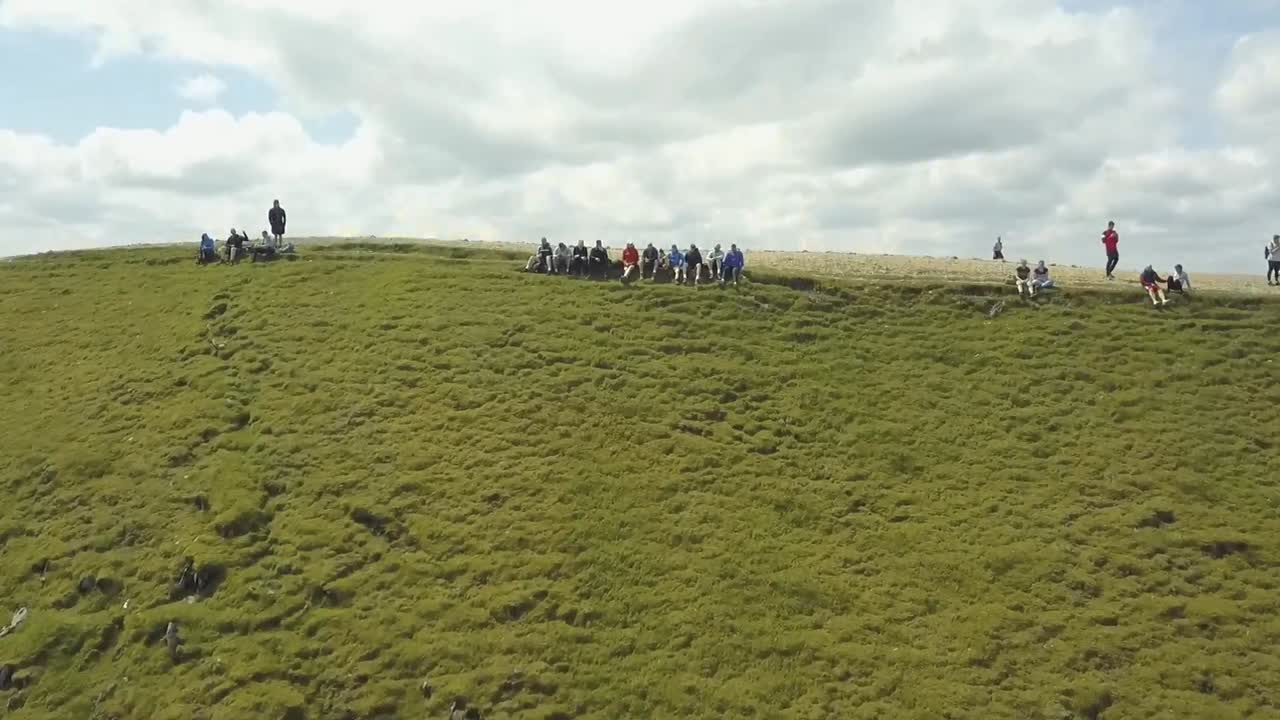 영국 호수 지구의 산꼭대기에 앉아 있는 사람들의 공중 드론 영상