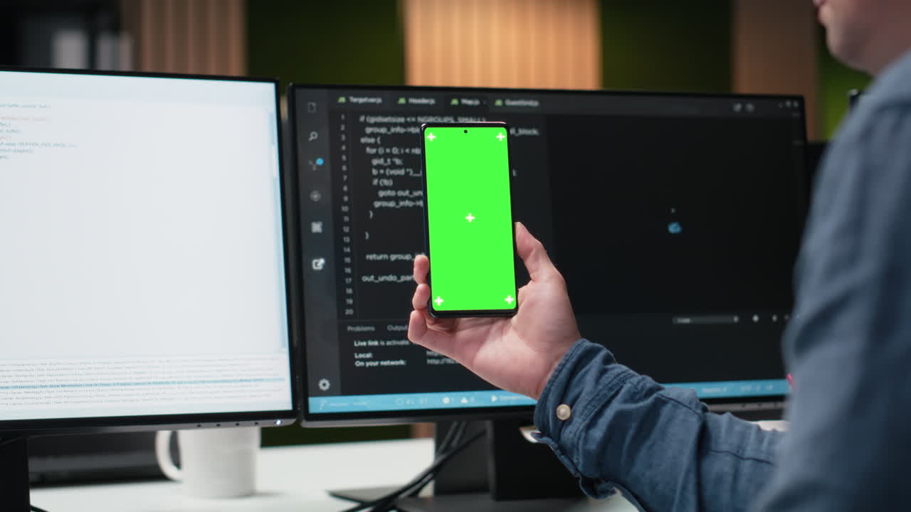 Developer Holding Smartphone with Green Screen in Modern Office
