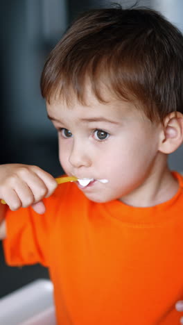 cute caucasian baby with white cream moustache eating. lovely kid eating yoghurt and cheering. close up. vertical video.
