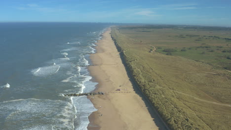 Aerial-shot-flying-over-a-nearly-empty-beach-during-COVID-pandemic,-people-social-distancing