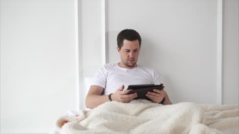 man reading on tablet in bed