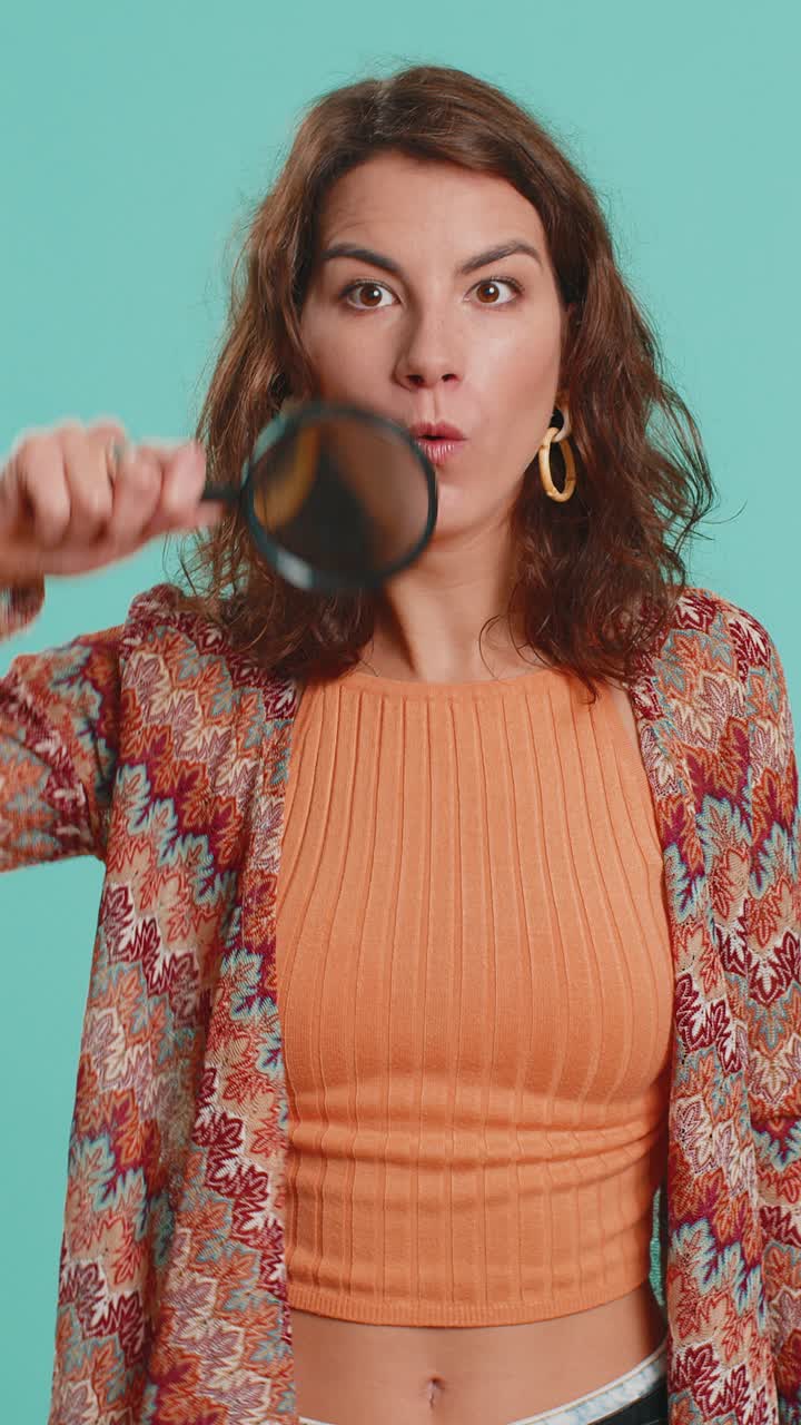 Investigator researcher woman with magnifying glass near face looking into camera with big zoom eye
