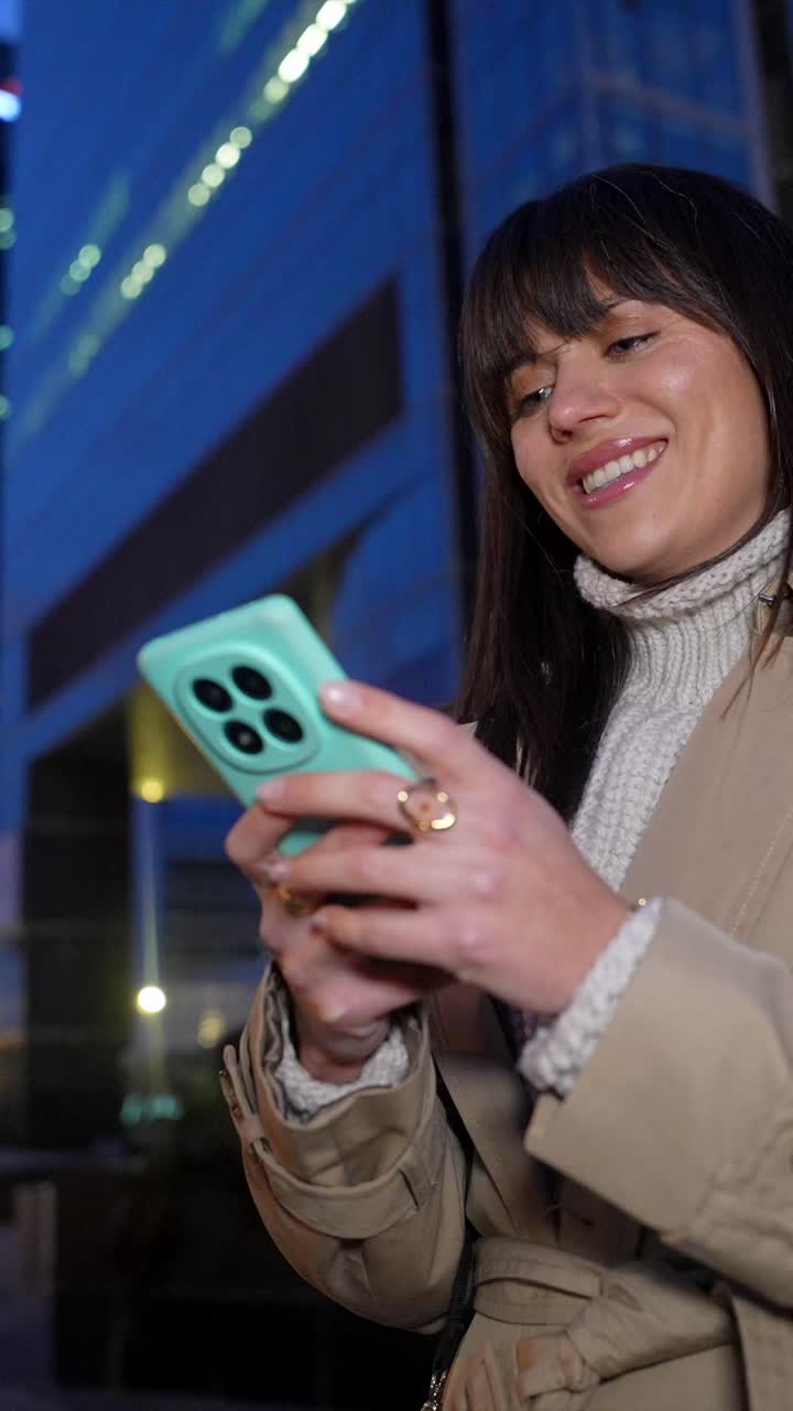 Donna giovane e felice che usa lo smartphone in città di notte