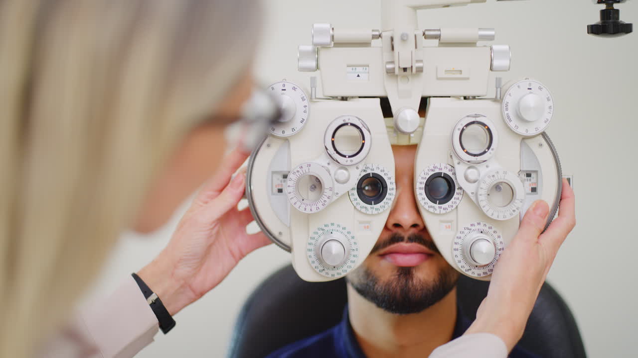 Optometrist using eye phoropter machine to examine