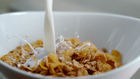 leche y frambuesas siendo vertidas en un tazón de cereales