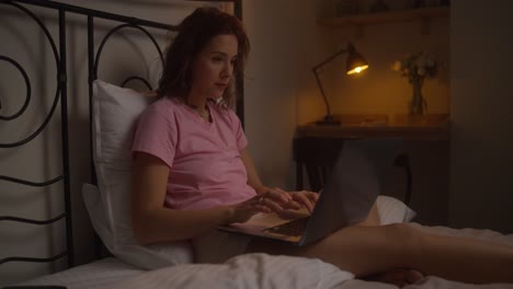 woman working on laptop in bed at night