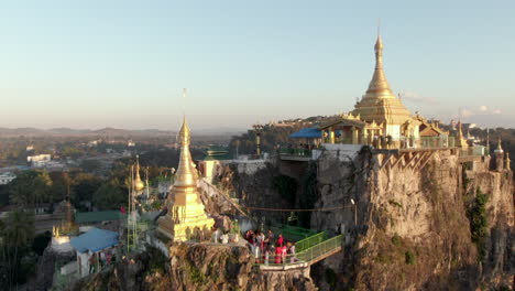 Ascending-drone-shot-showing-people-exploring-hidden-Sri-Mingala-Taung-Taw-Temple-Ares-during-sunset-in-Loikaw,-Myanmar