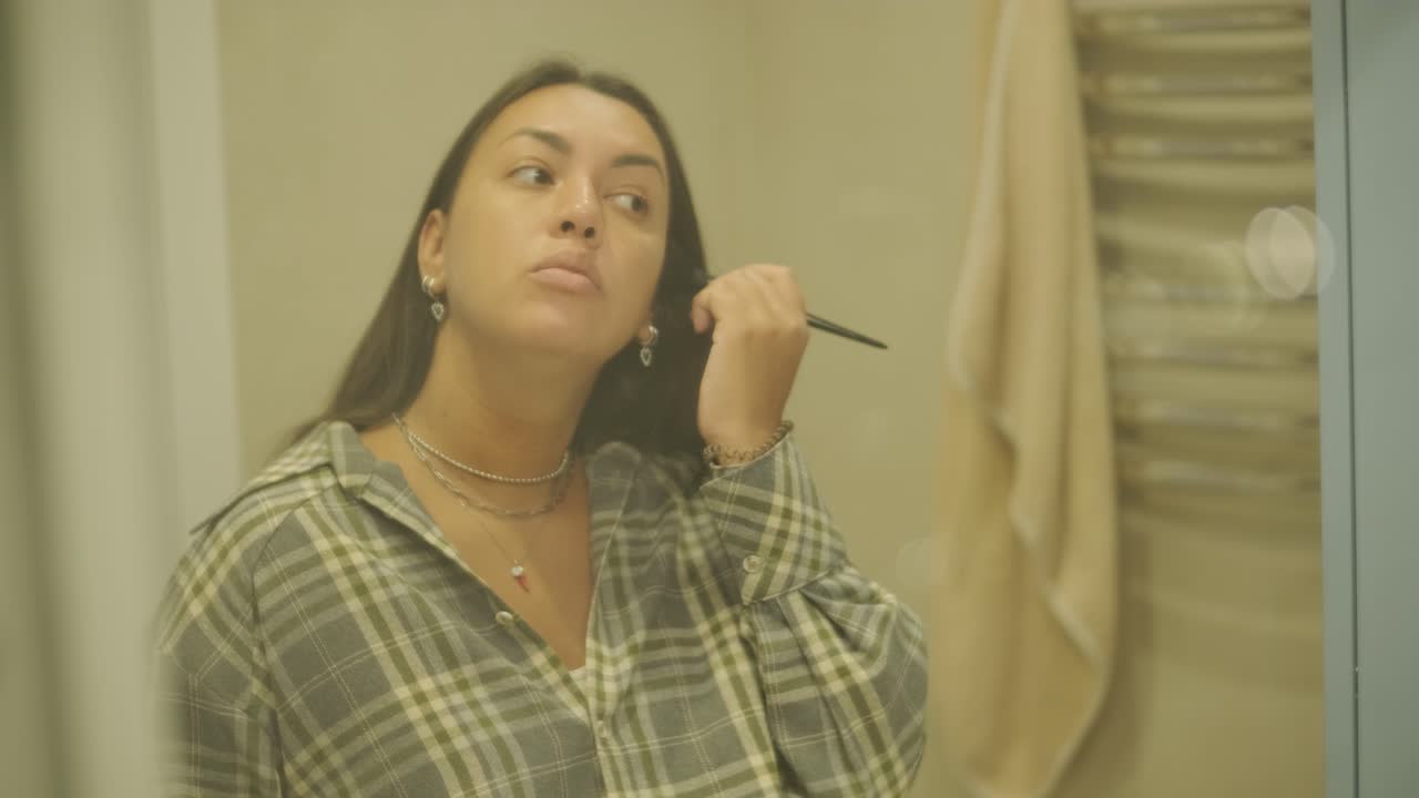 una mujer embarazada de pie cerca de un espejo en casa, vistiéndose. la escena refleja el cuidado de sí misma, la maternidad y la vida cotidiana en un entorno cálido y personal