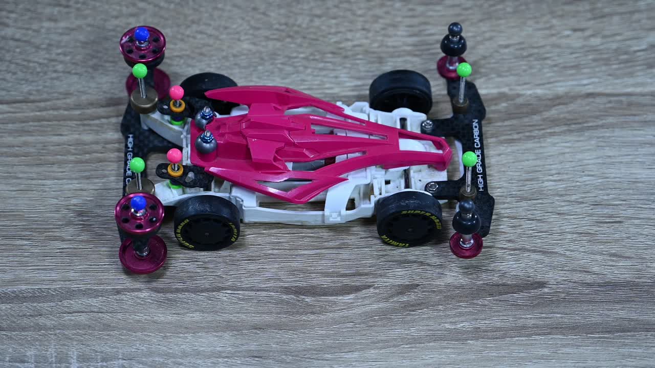 Zooming out on a white and pink Tamiya Mini 4X4 sports car that's placed on a table inside a toy shop in Bangkok, Thailand