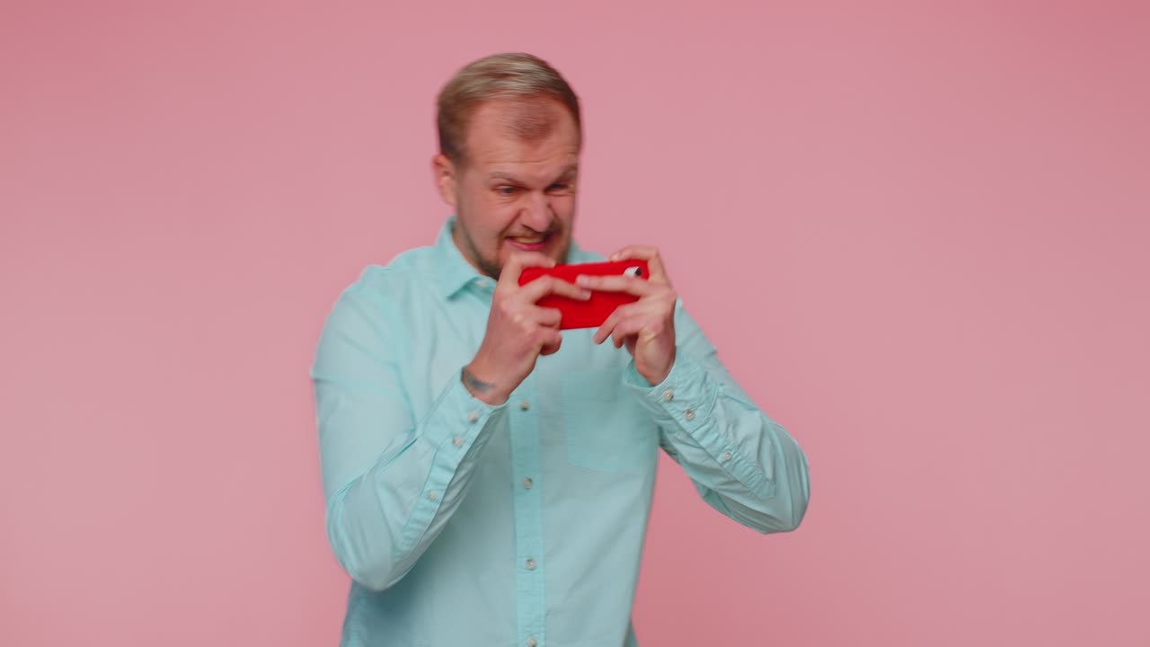 걱정스럽고 재미있고 중독된 관광객이  ⁇ 드폰으로 드라이브 레이싱 비디오 게임을 열정적으로 즐기고 있습니다.