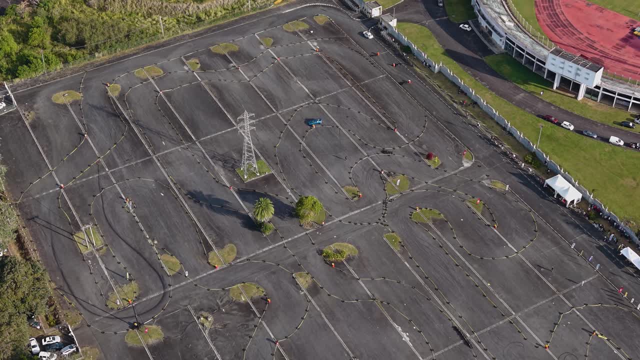 Aerial view of a car racing event at a parking lot in Mauritius, showing winding track patterns and a white vehicle navigating the course