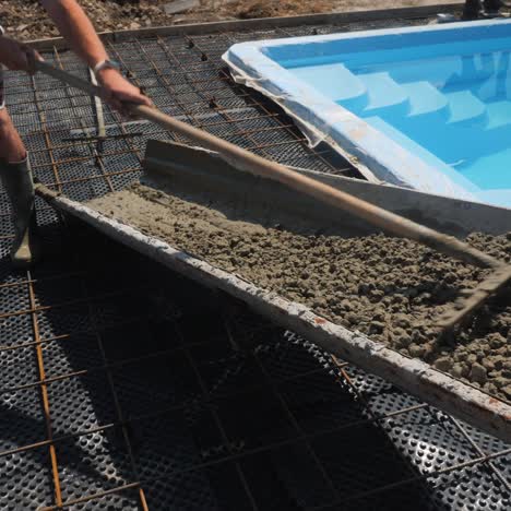 concrete flows down the gutters where workers make paving