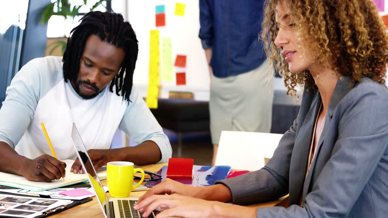 Female executive smiling while working with his colleague
