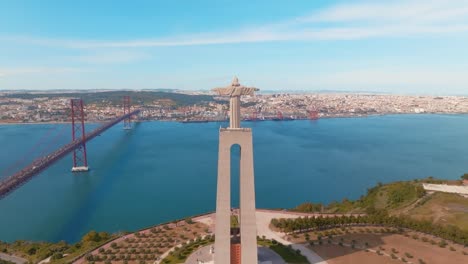 orbit shot of christ statue and suspended bridge over blue seascape, lisbon, portugal