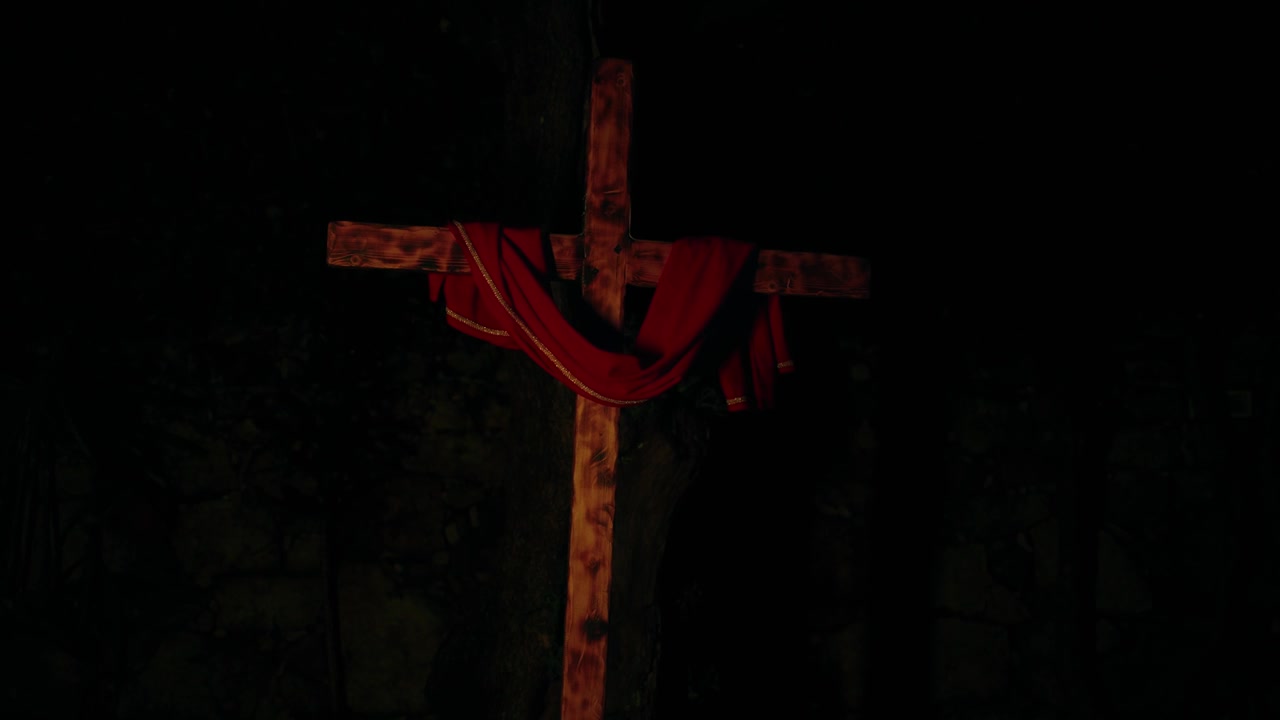 Croce di legno con telo rosso illuminata da luci multicolori lampeggianti di notte.