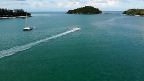 Luftaufnahme-Eines-Jet-Skis,-Der-Mit-Katamaranen-Durch-Eine-Bucht-Rast,-Malaysia-4k