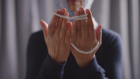 Close-Up-Of-Muslim-Woman-Wearing-Hijab-Praying-Holding-Prayer-Beads-At-Home-2