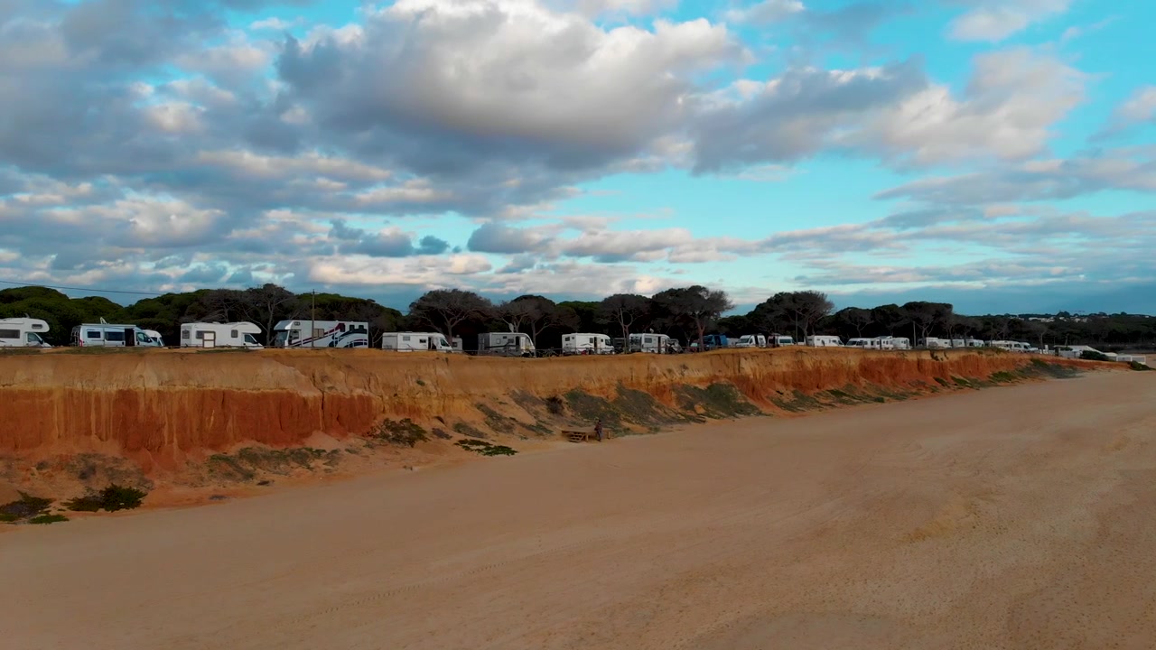 Beach with a cliff and pine trees and a cloudy sky in Algarve