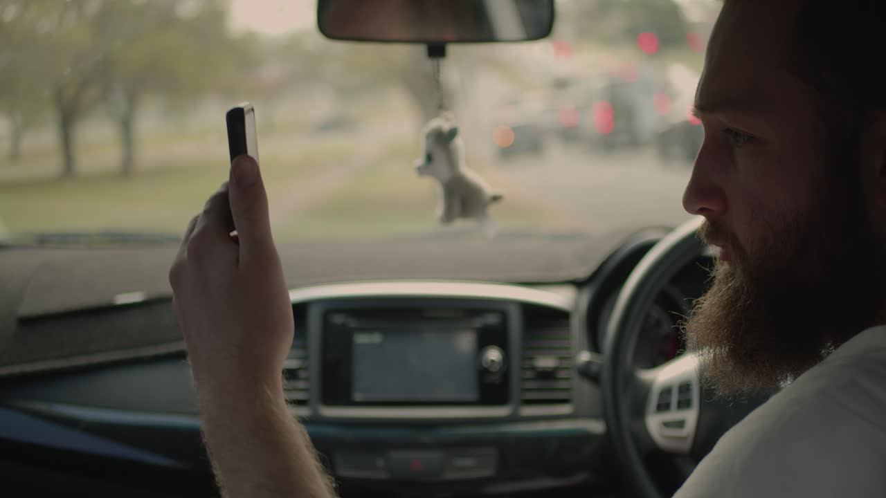 un hombre está estacionado en el lado de la carretera mientras pasa el tráfico, está mirando por la ventana de su pasajero con preocupación mientras habla con alguien sobre el teléfono interno de los coches