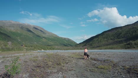 Hombre-Paseando-A-Su-Perro-Por-El-Lago-En-El-Parque-Nacional-De-Ånderdalen-En-La-Isla-De-Senja,-Lyngen,-Noruega