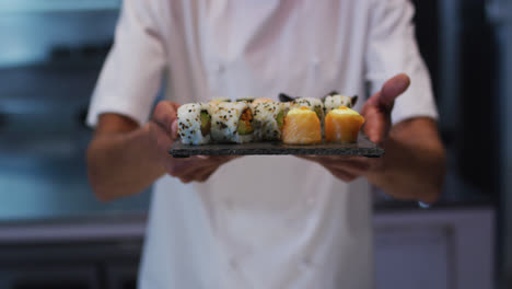 cocinero de raza mixta de pie en la cocina haciendo un buen plato de sushi
