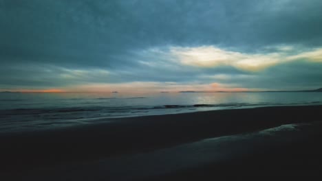 Vista-Aérea-Del-Cielo-Dramático-Con-Olas-Calmantes-Durante-La-Noche-En-La-Playa