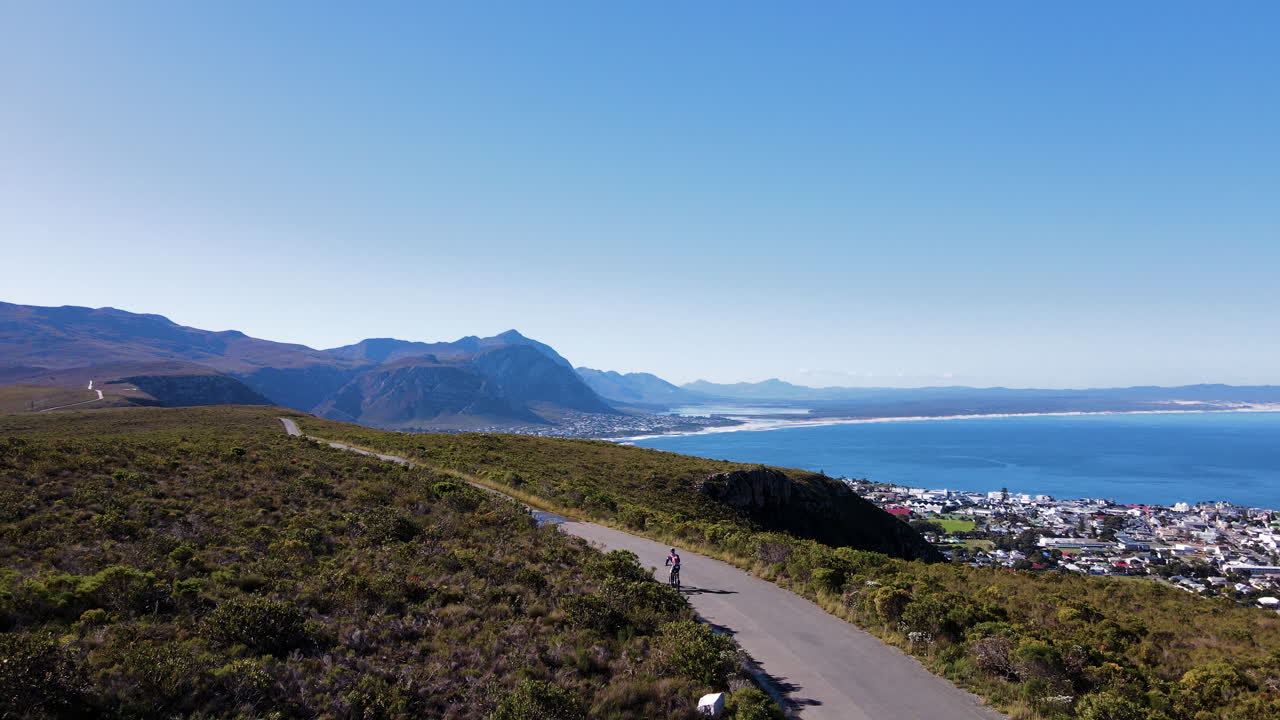 ciclista de mtc en una carretera de montaña con vistas a la costa y la bahía escénicas