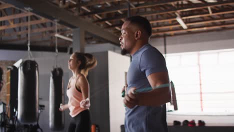 video of fit diverse woman and man jumping on jumping rope at gym