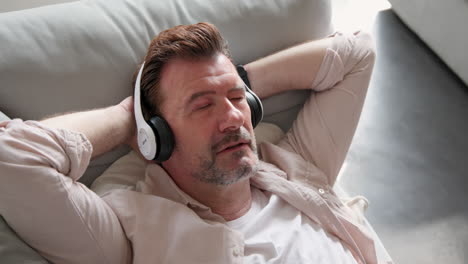 relaxing at home, senior man enjoying music with headphones on sofa