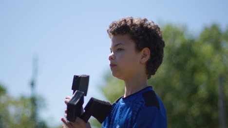 Handsome-young-boy-throwing-toy-axe-outdoors-in-a-park-midday