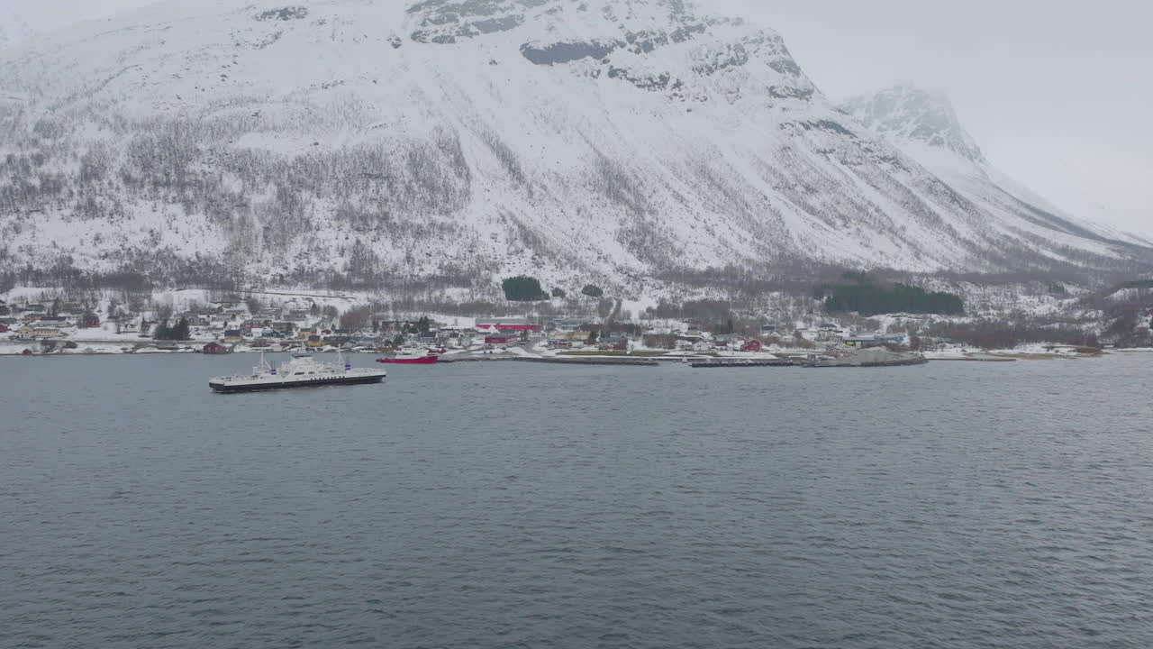ciudad de kåfjord y muelle al pie de una montaña en olddalen, noruega durante el invierno - toma aérea con drones