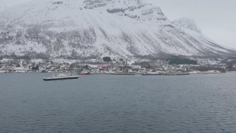 Kåfjord-Town-And-Pier-At-The-Foot-Of-A-Mountain-In-Olderdalen,-Norway-During-Winter---aerial-drone-shot