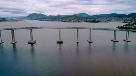 Aerial-side-view-of-a-bridge-standing-on-river-during-daytime